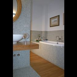 Casa B04 Foto del bagno padronale al piano primo. Rivestimento e pavimento in mosaico. Pedana in listelli di rovere.